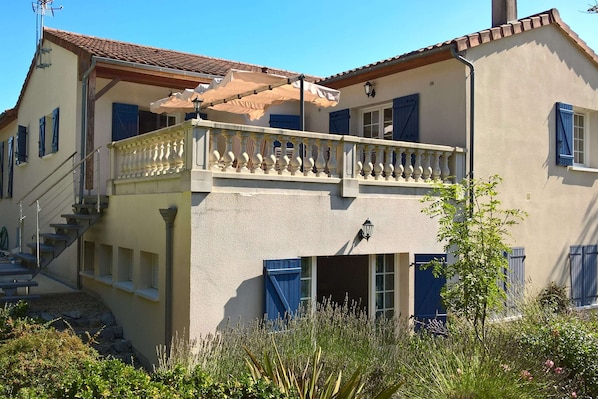 Un bâtiment à deux étages doté d’un balcon, d’un escalier et d’un petit jardin.