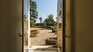 An open doorway leading to a courtyard with stone structures and trees. - Cottage in Chaleix Near Forest & Lake (Chalais)