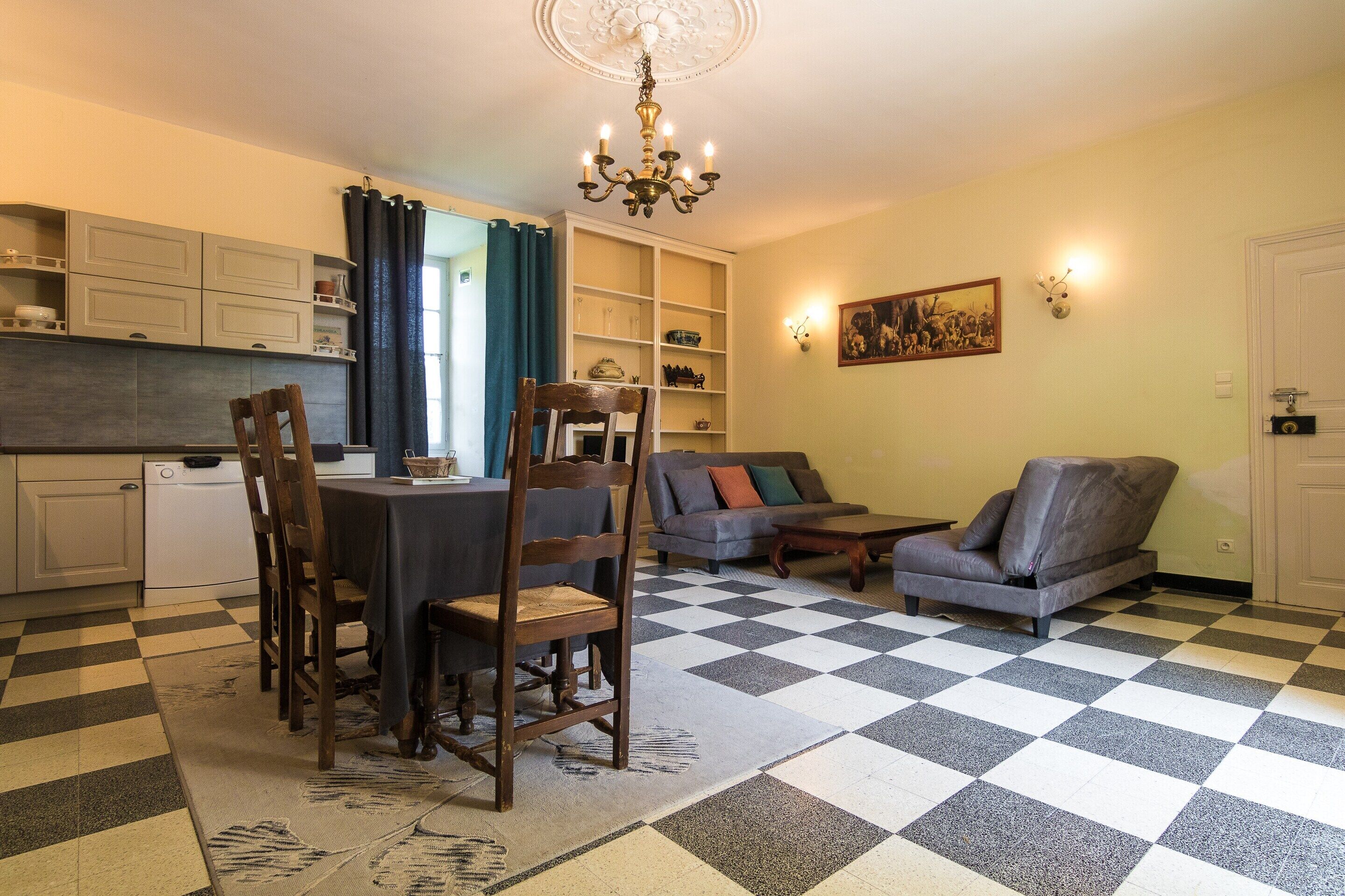 A dining area with a table and chairs, a sofa, a coffee table, and a chandelier.