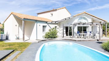 A two-story house with a swimming pool, outdoor seating, and a covered patio.