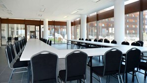 Uma sala de conferências com uma mesa comprida e cadeiras, janelas amplas e vista para o exterior.