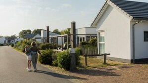 Une rue résidentielle bordée de maisons modernes, avec une chaussée asphaltée et un ciel dégagé.