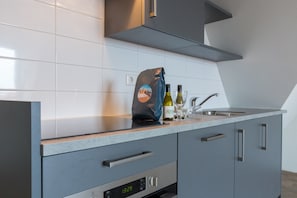 A modern kitchen with a digital clock, stainless steel appliances, and a bag of groceries on the counter.