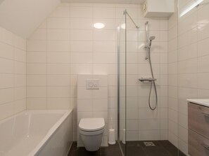 A modern bathroom with a bathtub, toilet, and glass-enclosed shower. - Spacious Holiday Home in Renesse near North Sea (Noordwelle)