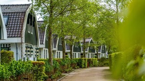 A row of traditional houses with sloped roofs and white walls, surrounded by well-maintained hedges and trees. - Nice Holiday Home With Dishwasher, in Schoorl (Schoorl)