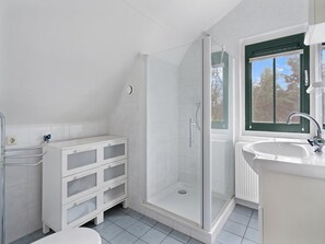 A modern bathroom with a shower, a sink, and a window.