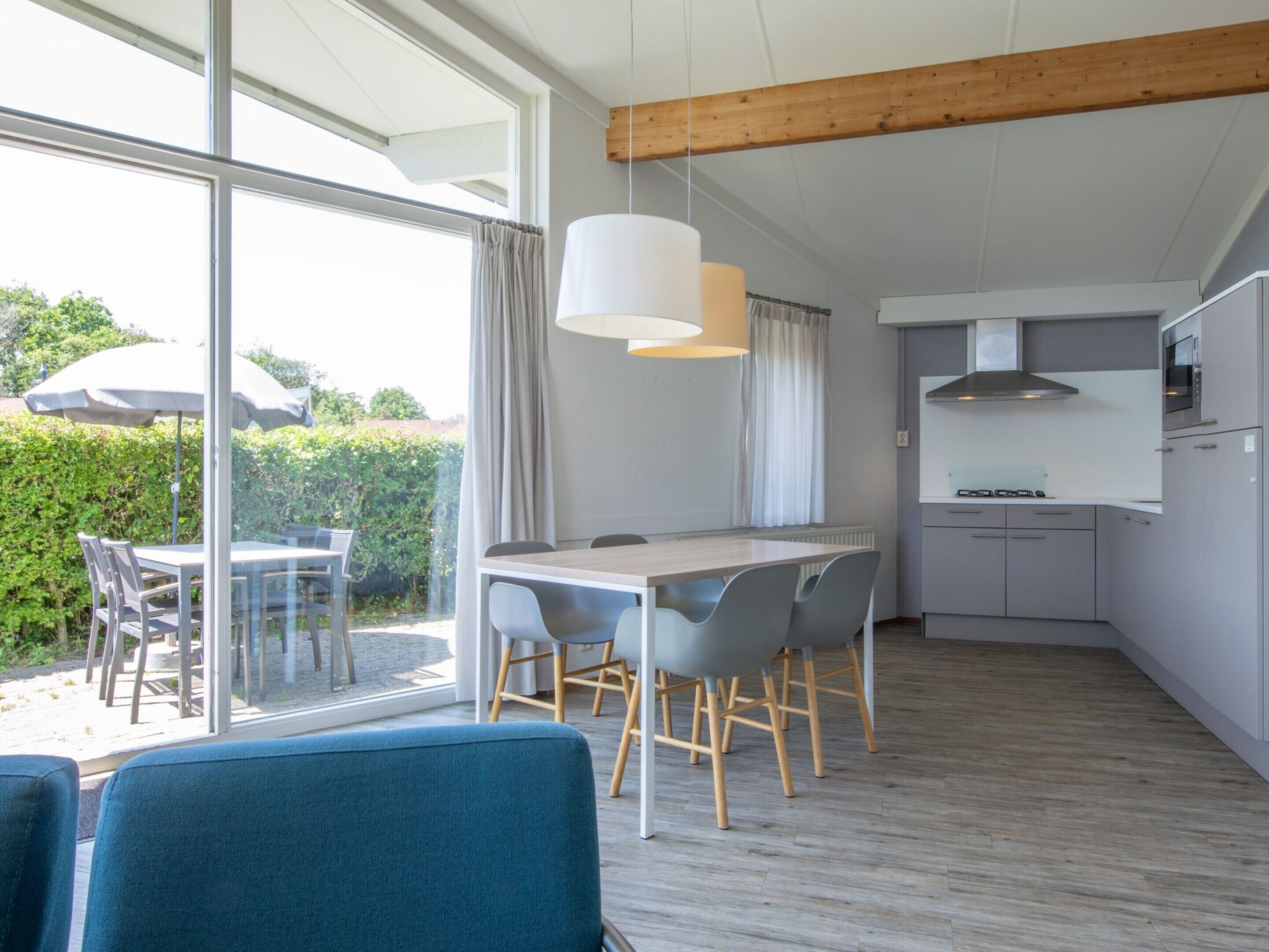 Uma cozinha moderna com forno e micro-ondas embutidos, área de jantar com mesa e cadeiras, e grandes janelas com vista para o exterior.
