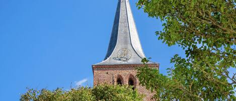A church tower with a pointed spire and a weather vane.