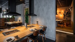 A modern dining area with a long wooden table, black chairs, and a black ceiling light fixture. - Villa With Sauna & Bubble Bath in Limburg (Roggel)