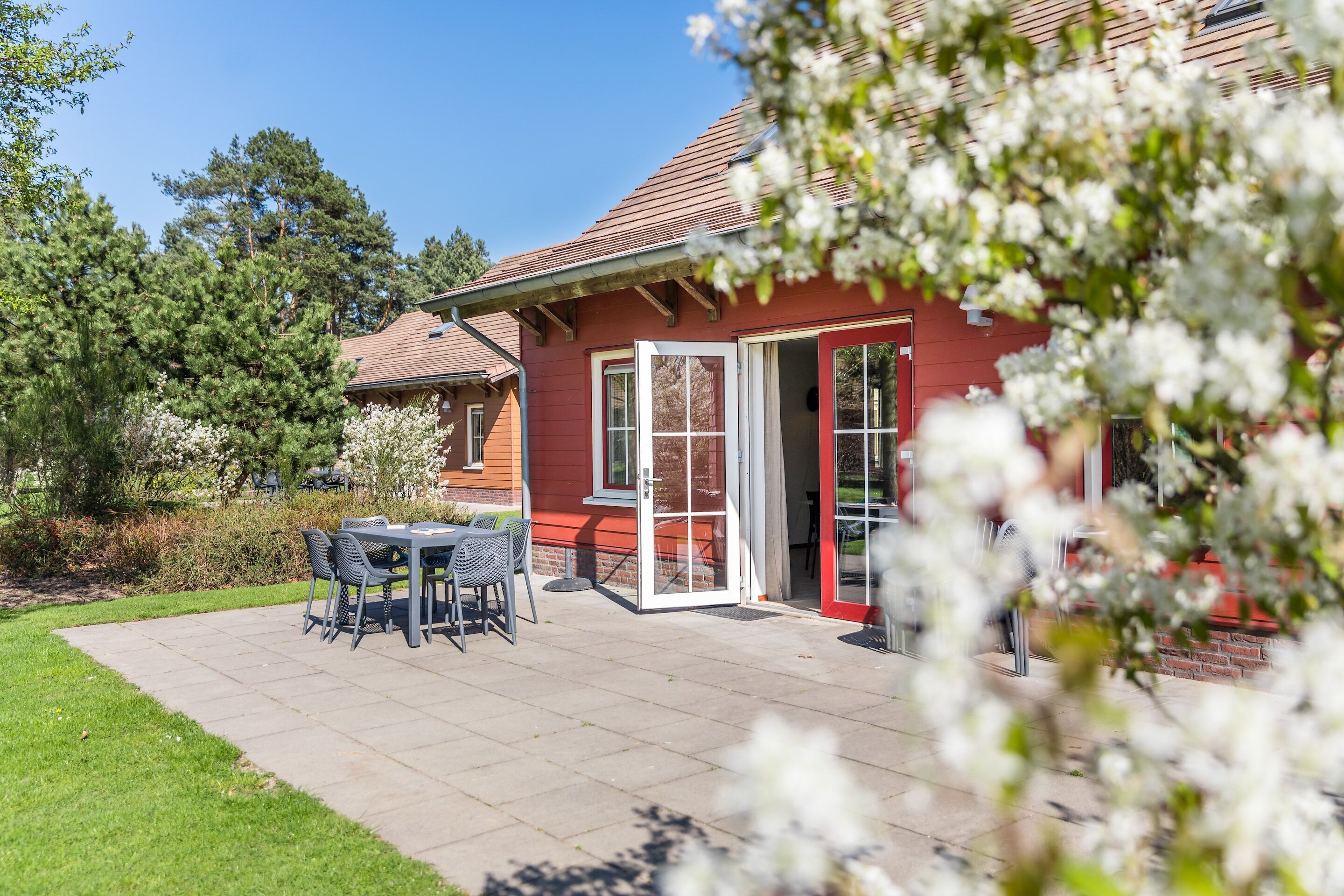 A red house with a patio, a table with chairs, and a door.