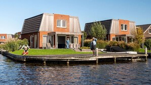 Une maison située au bord d’un canal, dotée d’un patio couvert, d’un petit quai pour bateaux et d’une zone herbeuse.