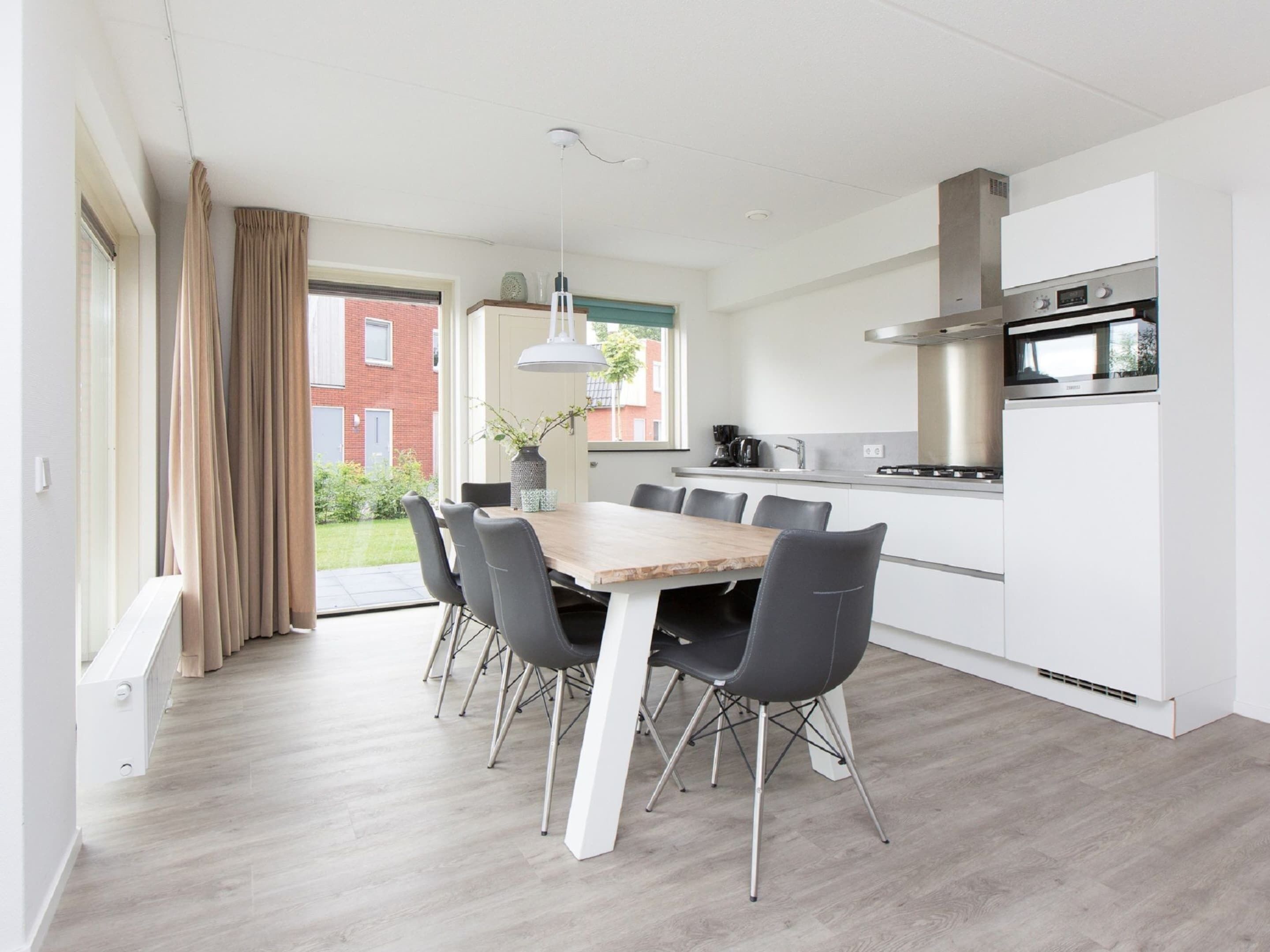 A modern kitchen with white cabinets, a stainless steel range hood, and a built-in oven.