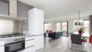 Une cuisine moderne avec des meubles blancs, un four encastré et une hotte de cuisine en acier inoxydable.