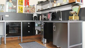 A modern kitchen with stainless steel appliances, wooden cabinets, and a variety of kitchenware displayed on shelves.