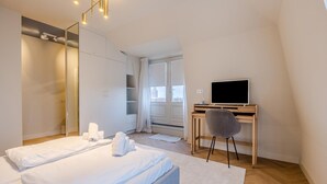 Ein modernes Schlafzimmer mit einem großen Bett, einem Schreibtisch mit Computer und einem Stuhl.