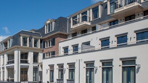 Ein modernes Mehrfamilienhaus mit Balkonen, großen Fenstern und einer flachen Dachfläche.