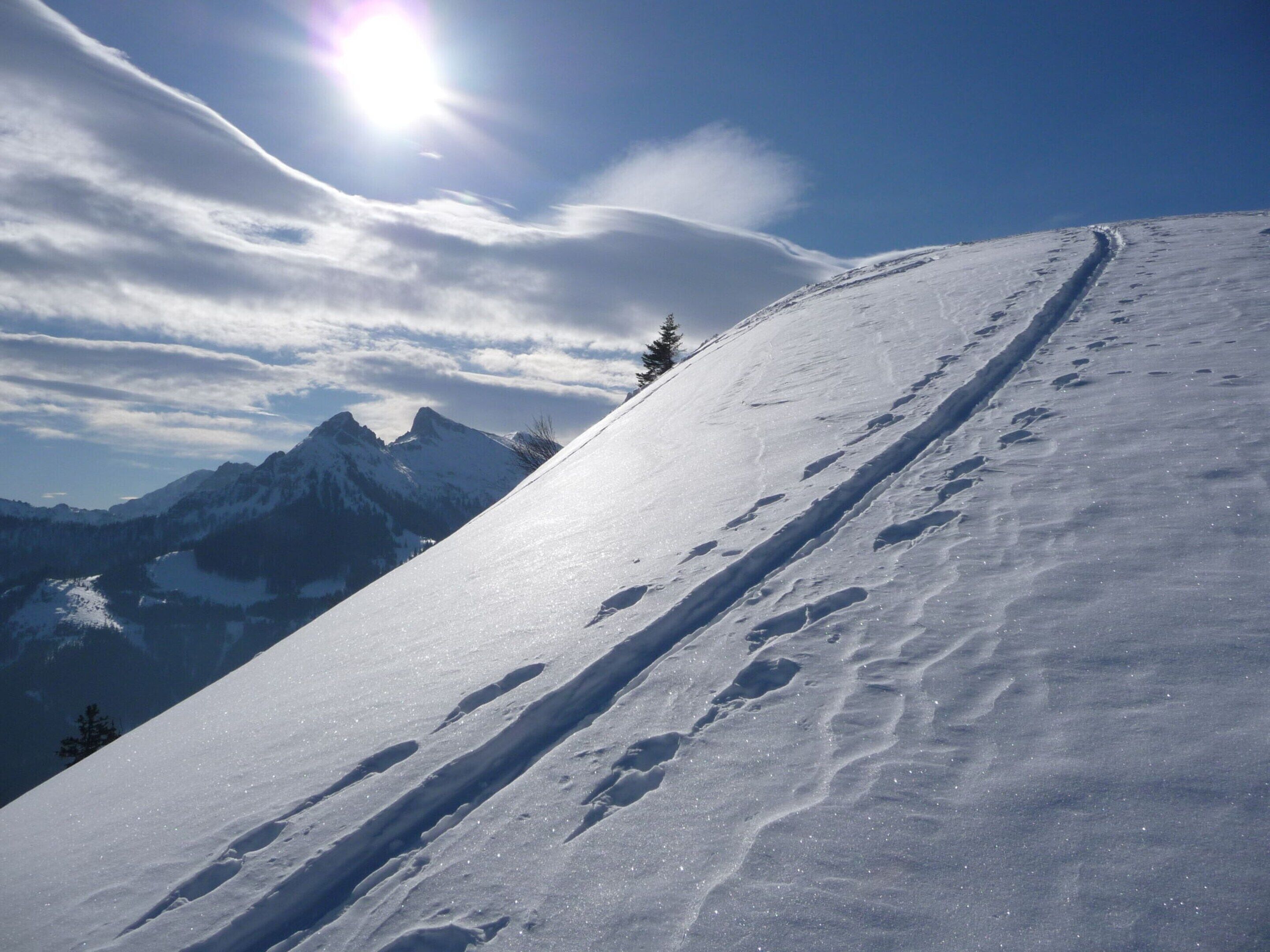 A snowy mountain slope with a clear sky and distant peaks.