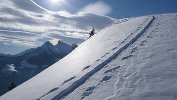 A snowy mountain slope with a clear sky and distant peaks.