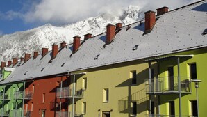 A row of colorful buildings with snow-covered roofs and a mountain in the background.