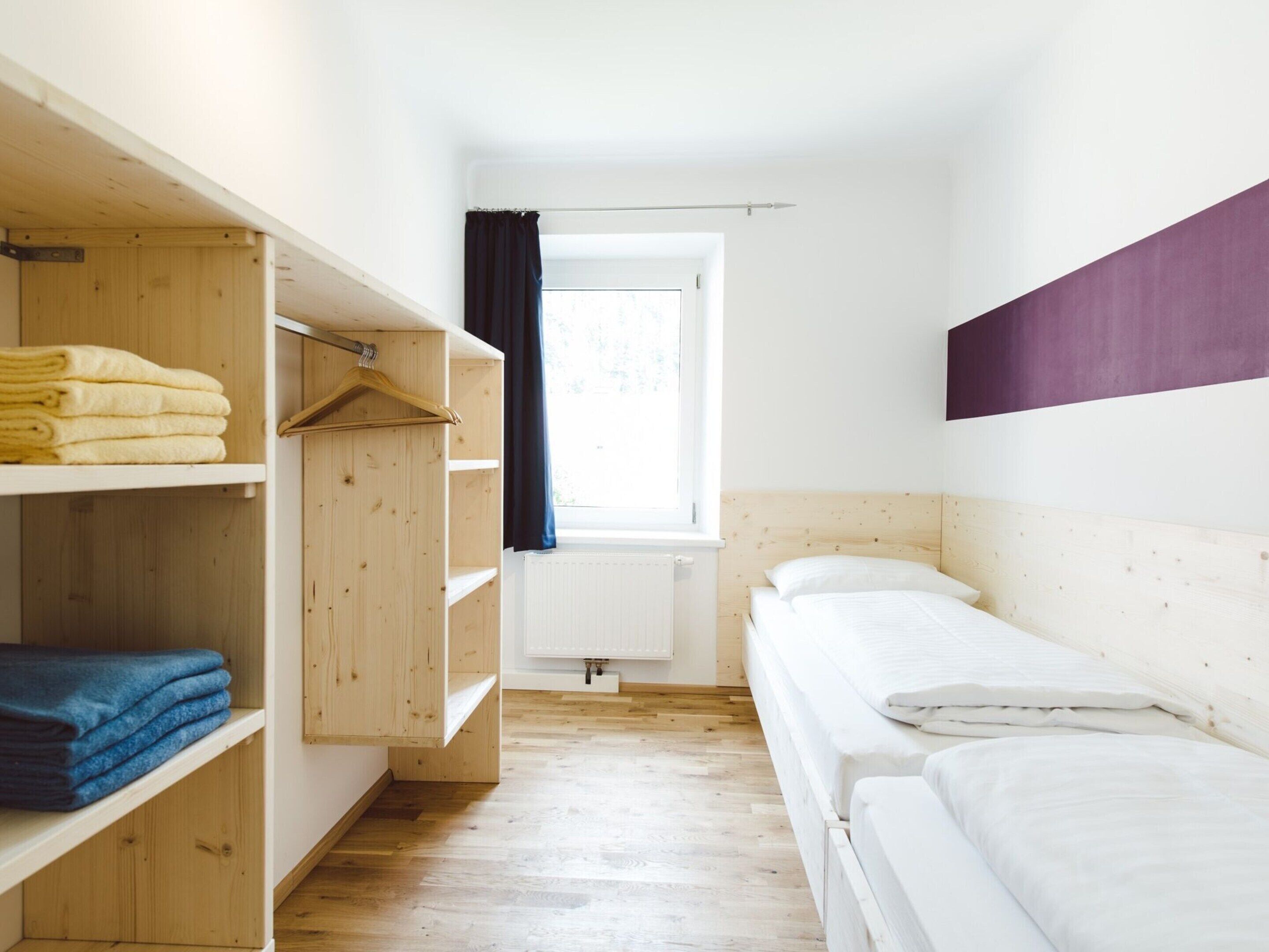 Ein Zimmer mit Etagenbett, Holzschrank und Heizkörper.