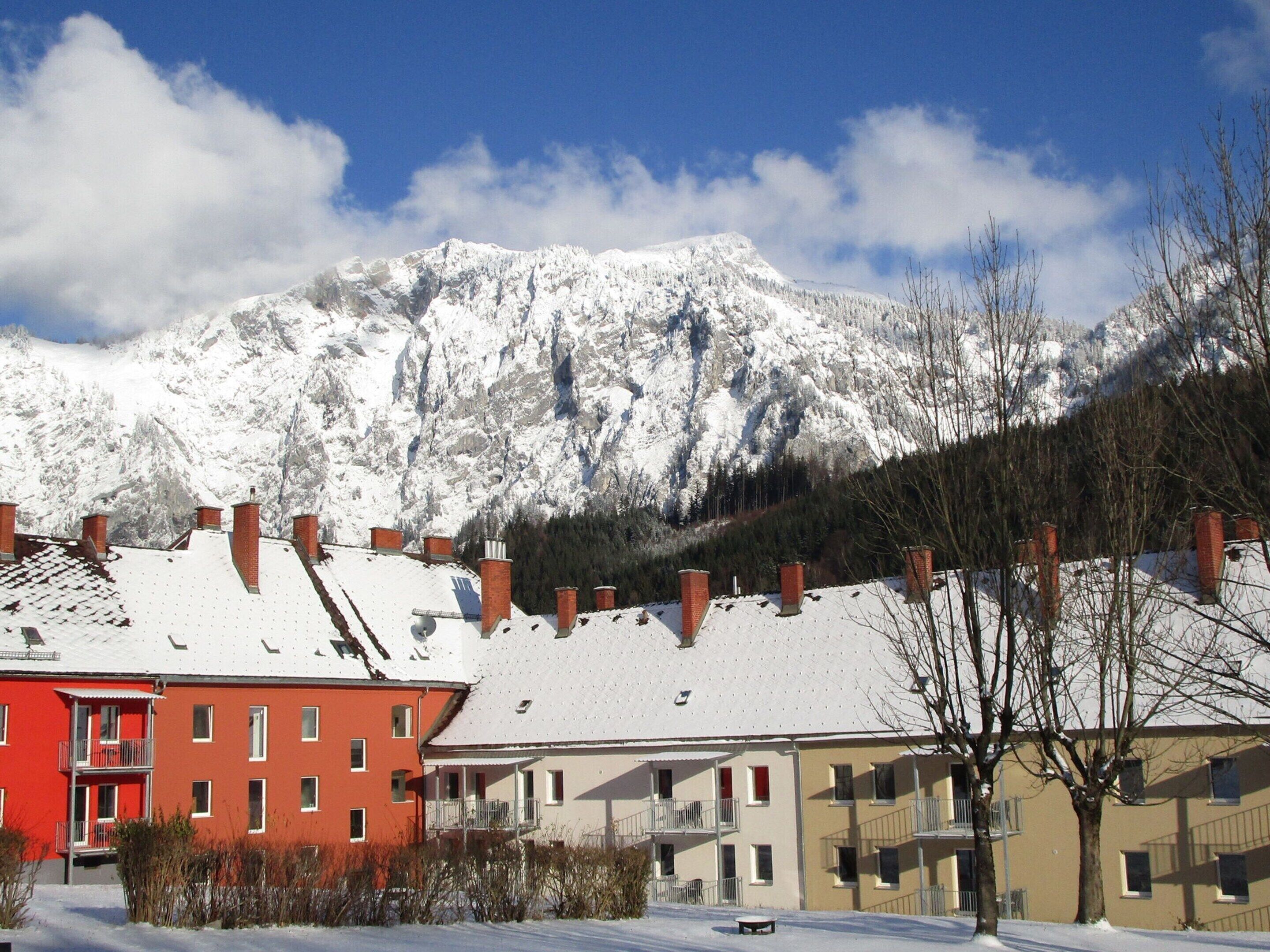 A residential area with snow-covered buildings and a mountain in the background.