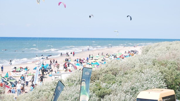 A beach with multiple kites flying, people on the sand, and tents set up. - Bungalow Near Baltic Sea (Neubukow)
