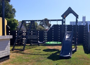 Children can play on the slide, swing set, and climbing structure in this backyard playground.