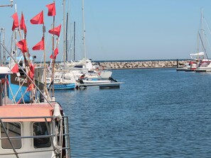 Boats docked at the marina, surrounded by a breakwater of large rocks.