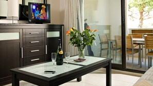 A modern hotel room with a glass dining table, a sofa, a TV, and a balcony with a dining area. - Luxury Apartment With Large Terrace (Mandelieu-La-Napoule)