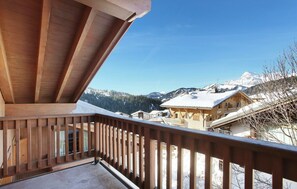 A wooden balcony with a view of snow-covered houses and mountains. - Apartment in Le Village Complex, France (Notre-Dame-de-Bellecombe)