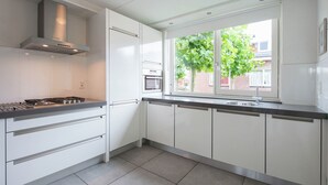 A modern kitchen with white cabinets, a gas stove, a built-in oven, and a window with a view of the outside. - Nice House With Dishwasher, Near Amsterdam (Uitgeest)