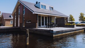 A modern house with a large garage, a covered patio, and a dock extending into a body of water. - Nice House With Dishwasher, Near Amsterdam (Uitgeest)