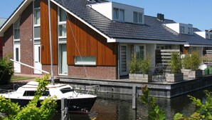 A modern house with a sloped roof, a dock, and a boat. - Nice House With Dishwasher, Near Amsterdam (Uitgeest)
