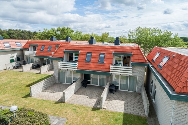 A row of modern, two-story houses with red roofs, large windows, and a flat roof extension. - Apartment on Texel Near De Koog Beach (De Koog)