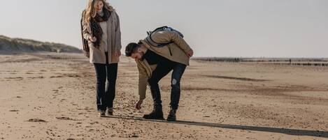 Two people walking on a sandy beach with a clear sky.
