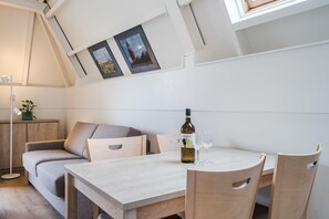 A cozy room with a wooden table, two chairs, a sofa, and a small cabinet. - Apartment on Texel Near De Koog Beach (De Koog)