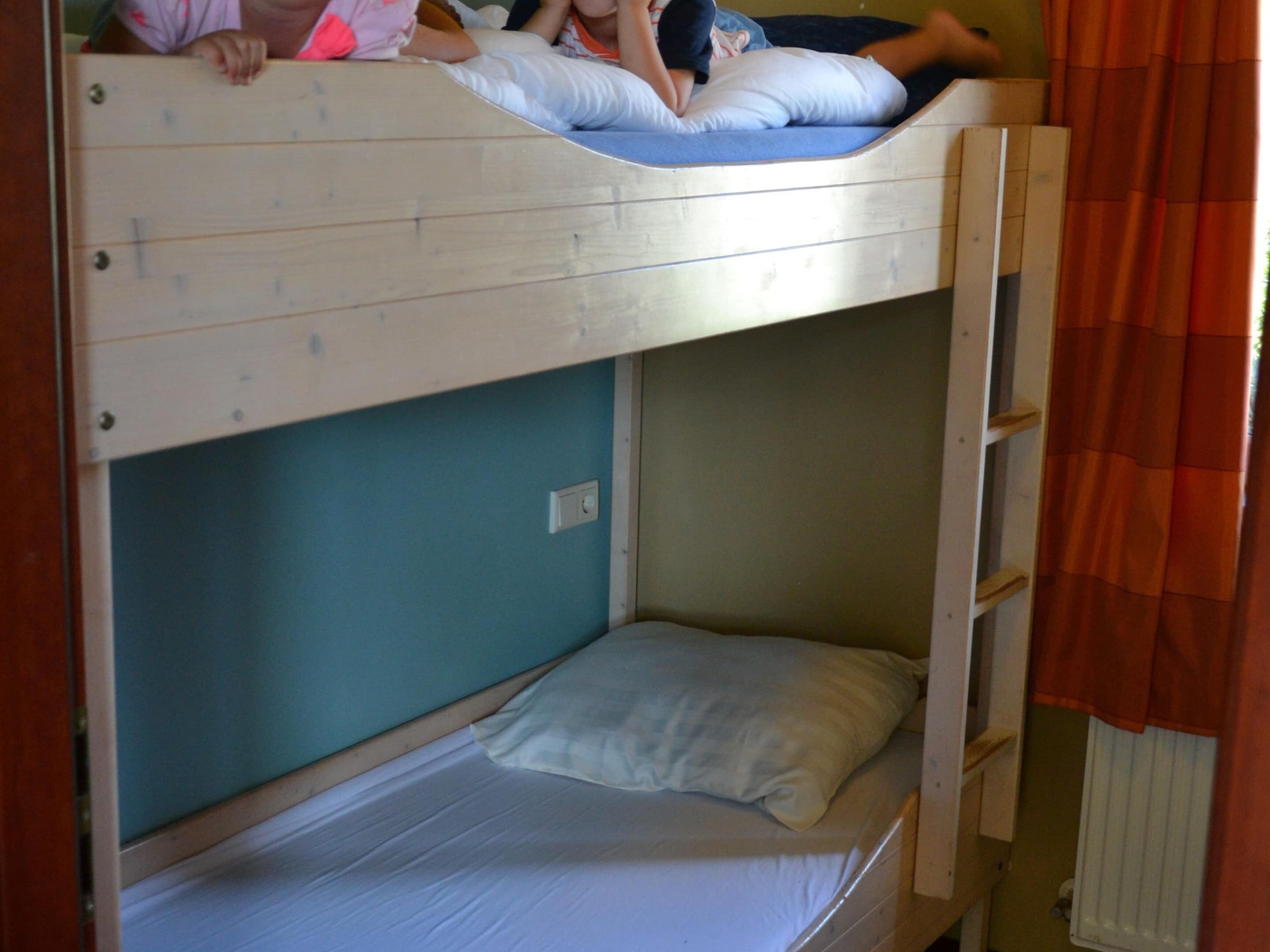 Een slaapkamer met een stapelbed en een ladder aan de rechterkant.