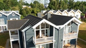 A two-story house with a balcony, a deck, and a patio area. - Bungalow by the Sea With Sauna in Germany (Sierksdorf)