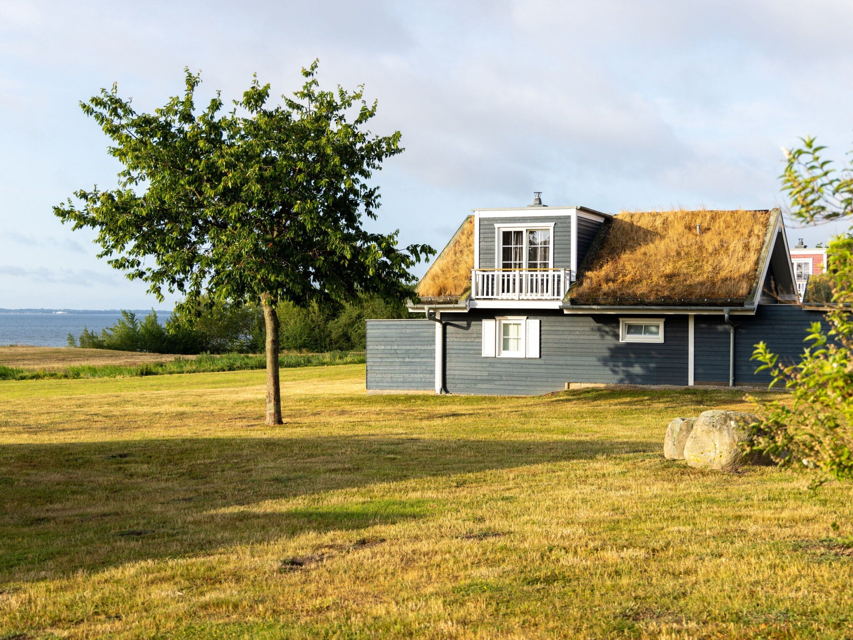 Una casa con techo de paja, un balcón y vista al mar.