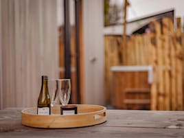 A wooden tray with a bottle of Jacobs Creek wine, two glasses, and a candle labeled Rich Mahogany on a wooden table.