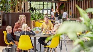 Un restaurante con mesas en el interior, decoración de madera y lámparas colgantes.