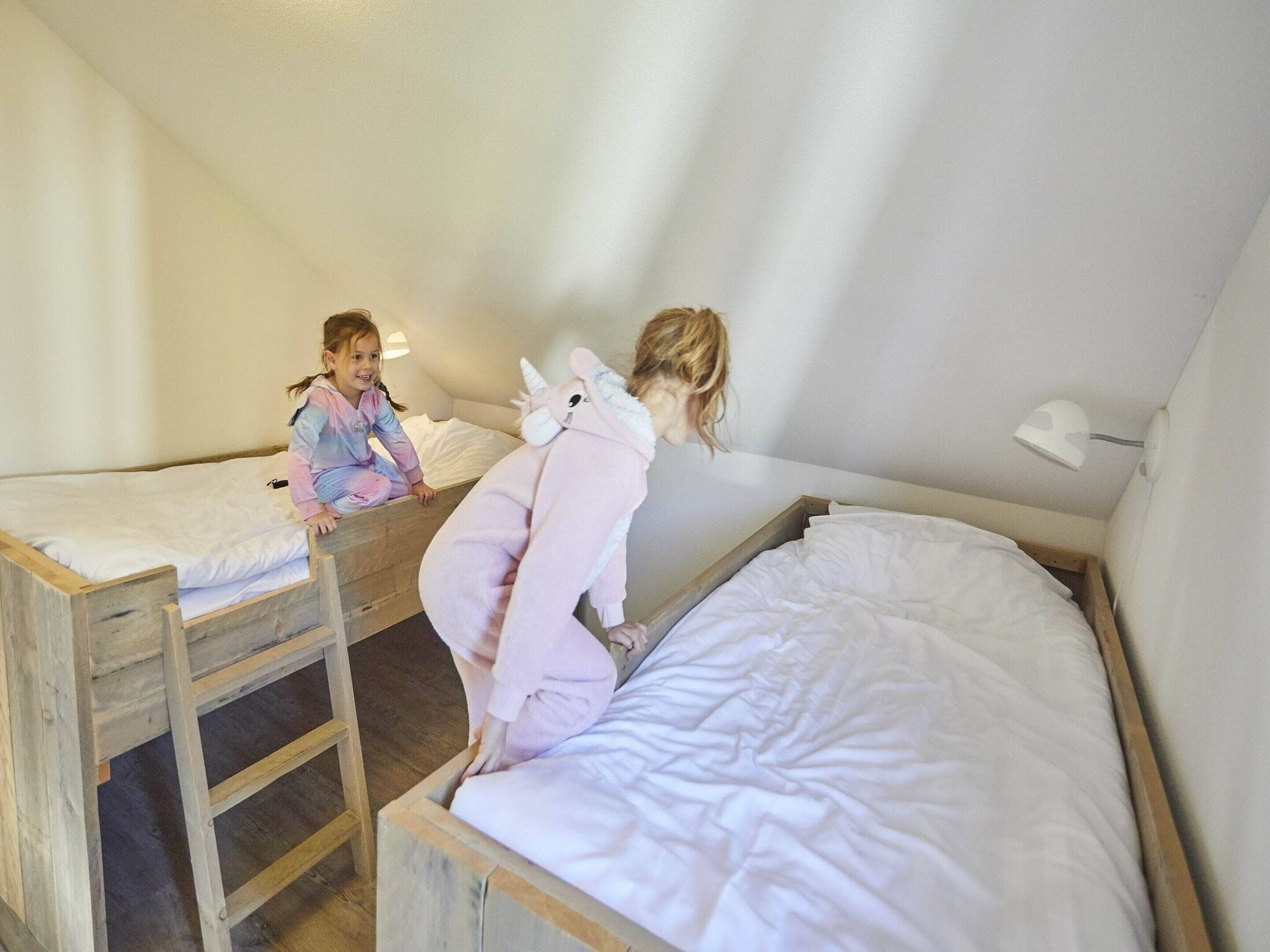A room with two bunk beds, a wooden ladder, and a white ceiling lamp.