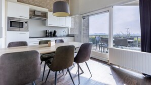 A modern kitchen with a dining area, large windows, and a view of the outdoors. - Holiday Home in Kamperland Near the Beach (Kamperland)