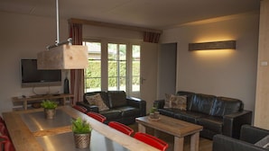 Una sala moderna con una mesa de comedor de madera, dos sofás y un televisor.