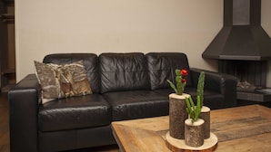 Una sala de estar moderna con un sofá de cuero negro, una mesa de centro de madera y una chimenea.