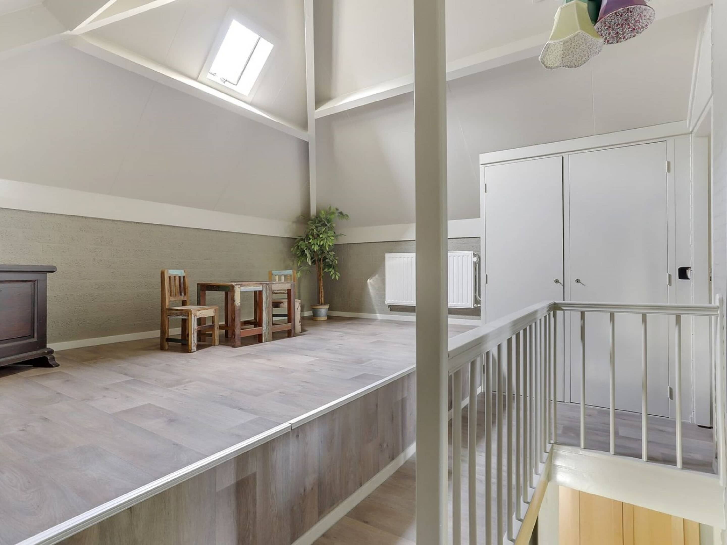 A spacious loft with high ceilings, a mezzanine level, and a view of the sky through skylights.