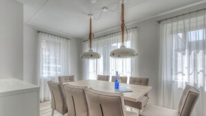 Ein moderner Essbereich mit einem runden Tisch, beigen Stühlen und Pendelleuchten.