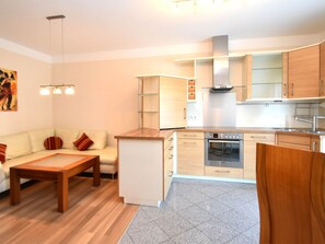 Cozy living area with sofa, compact kitchen with oven, and small dining area with chair.