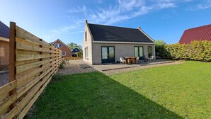 A modern house with a brick exterior, a tiled roof, and a small patio with outdoor furniture. - Nice House with Dishwasher near Wadden Sea (Tzummarum)