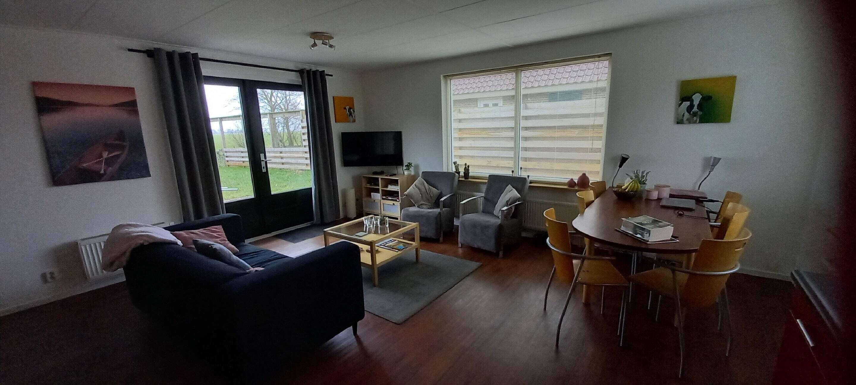 A living room with a sofa, coffee table, TV, and dining area with chairs and a table.